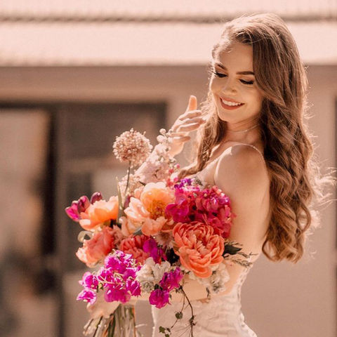 Bride holding a vibrant bouquet of peonies and seasonal flowers