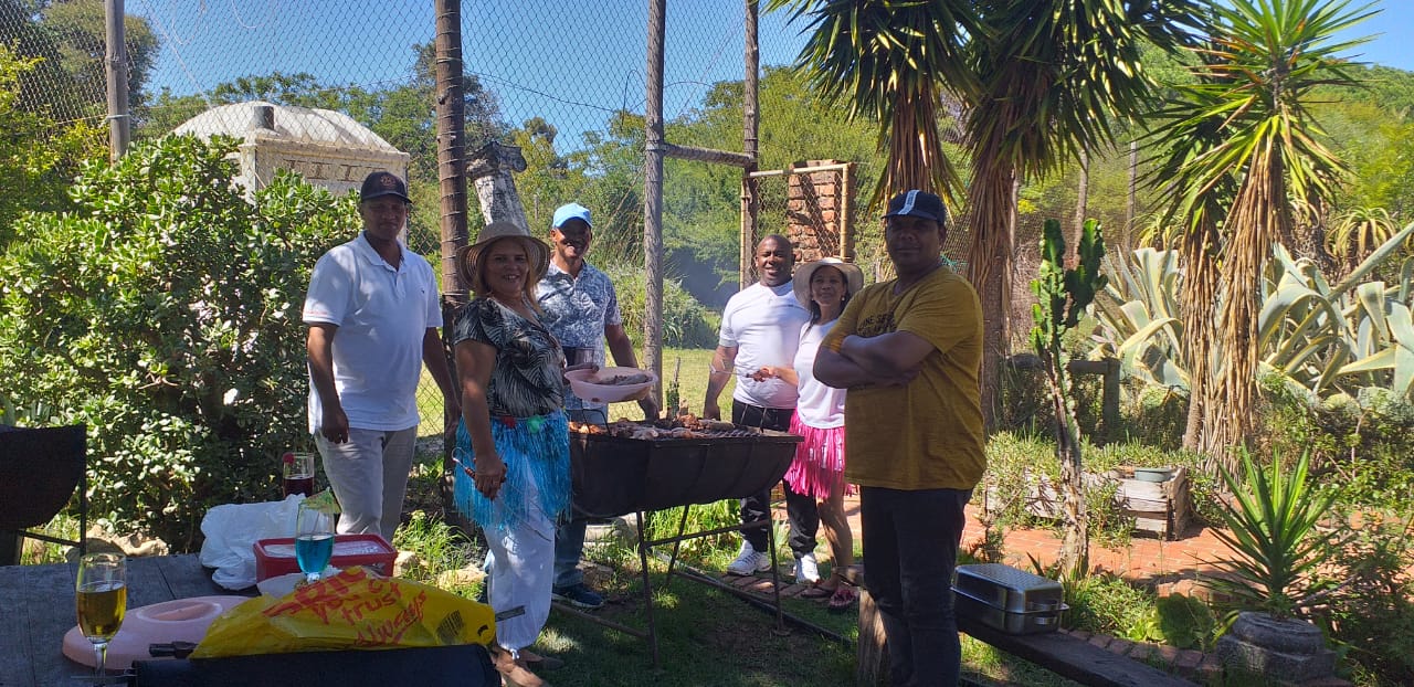Group of people enjoying a braai outdoors in a garden setting.