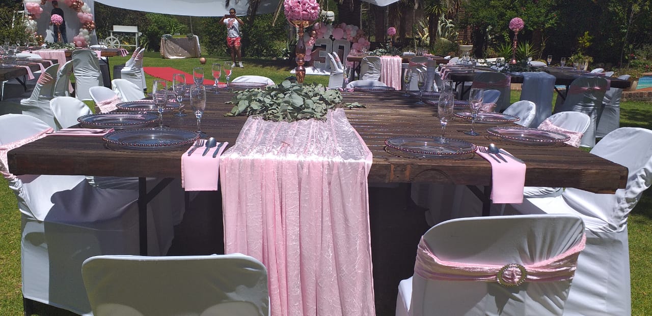 Outdoor event table with pink drapery and white chairs