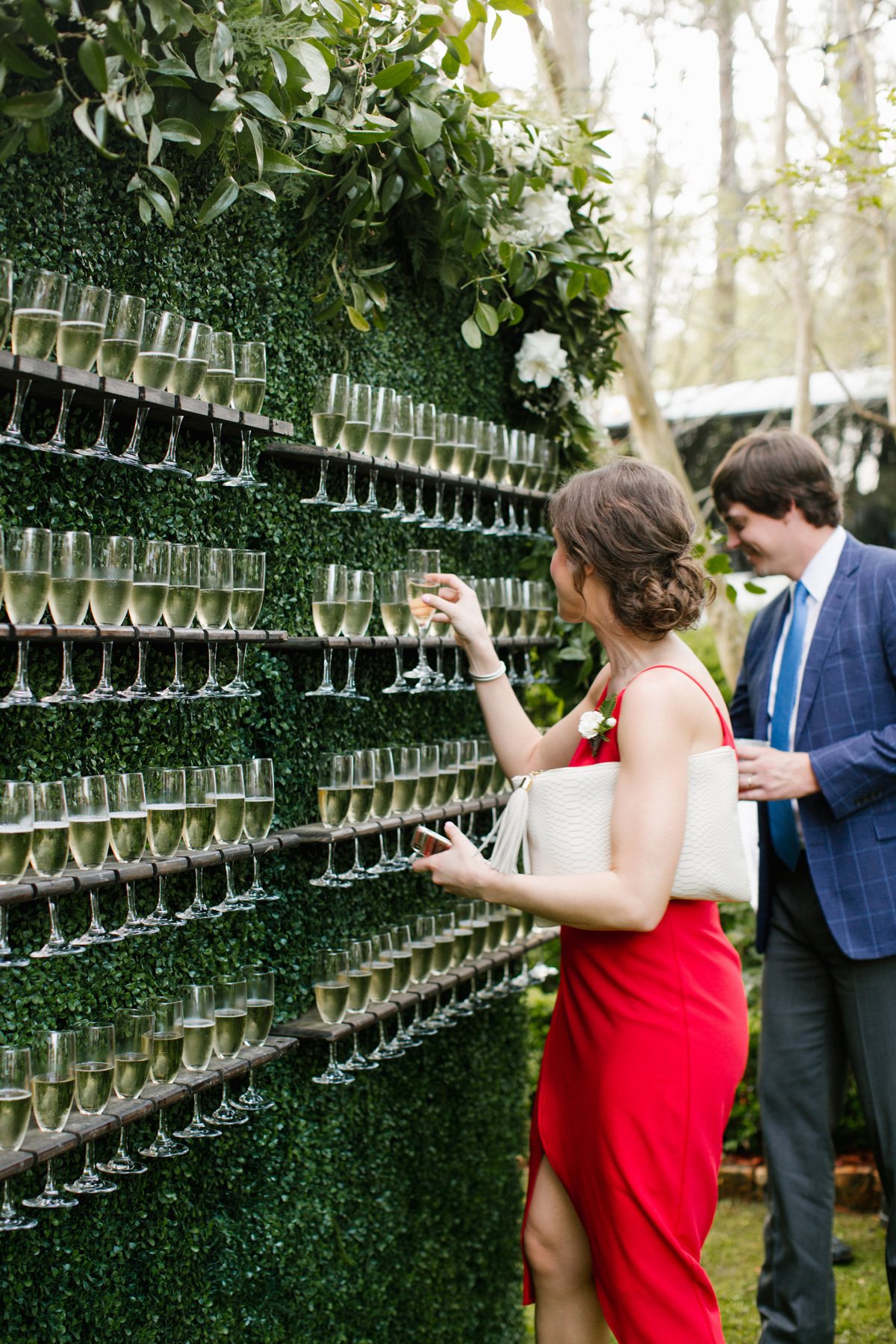 Champagne wall with glasses and greenery backdrop