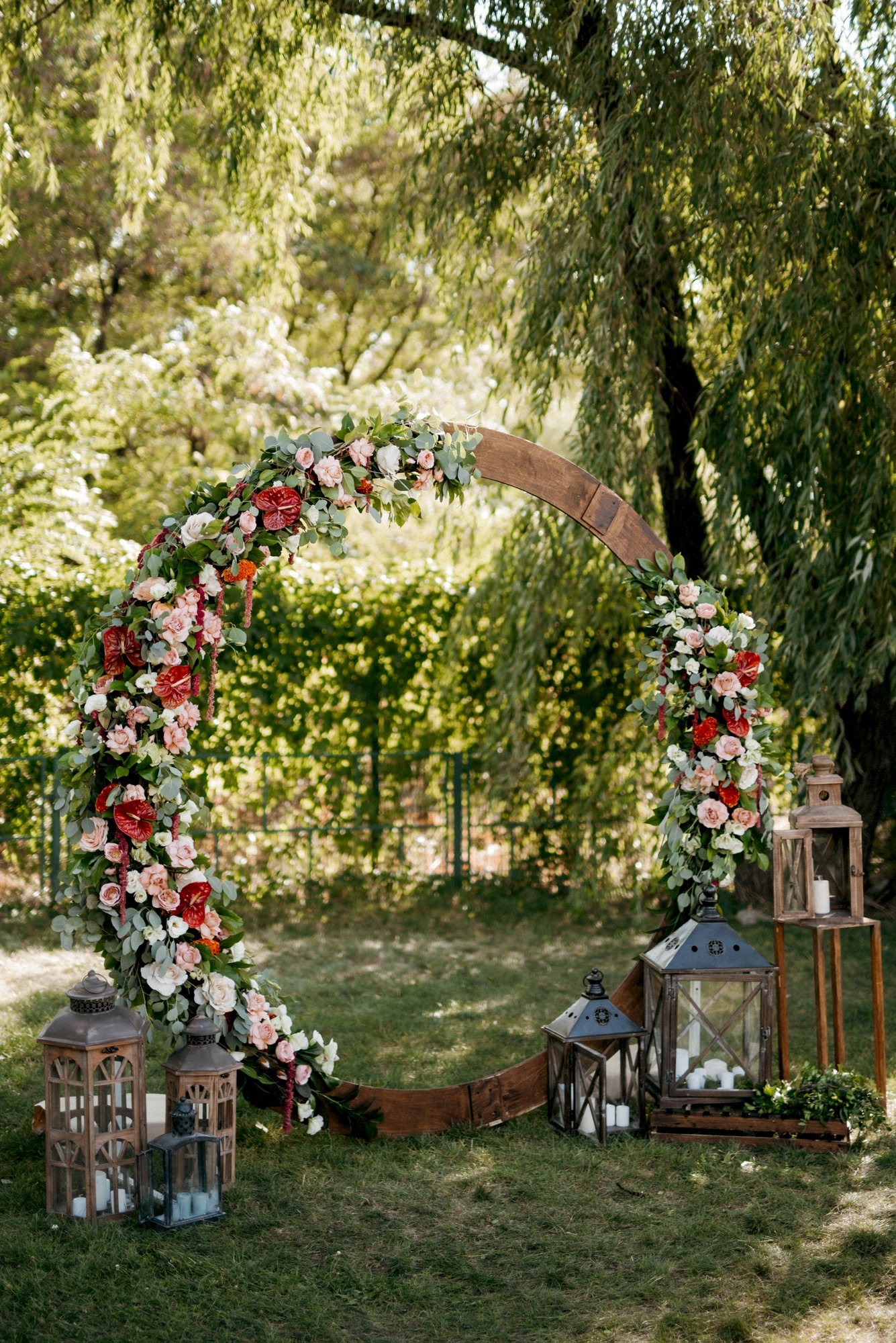 A floral arch with lanterns set on grass