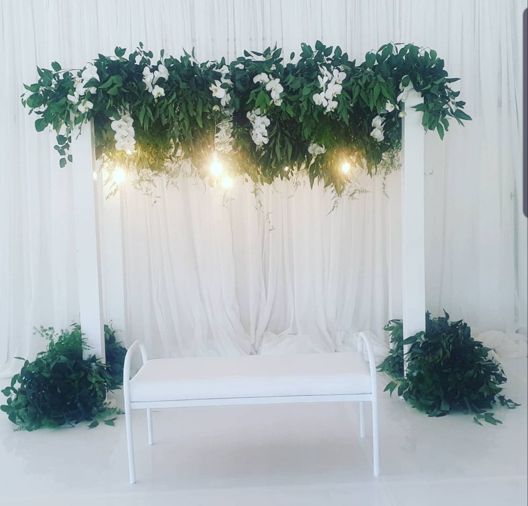 Floral altar with white bench and greenery
