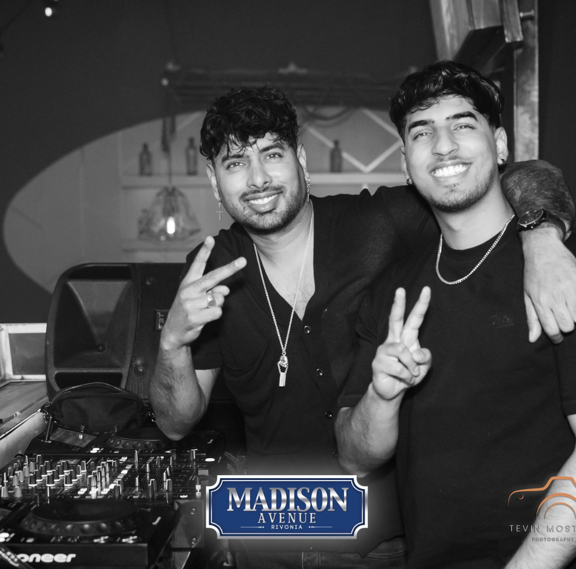 Two DJs smiling at a turntable setup in Madison Avenue