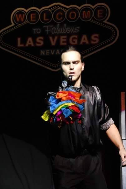 Magician performing with colorful scarves in front of a Las Vegas backdrop