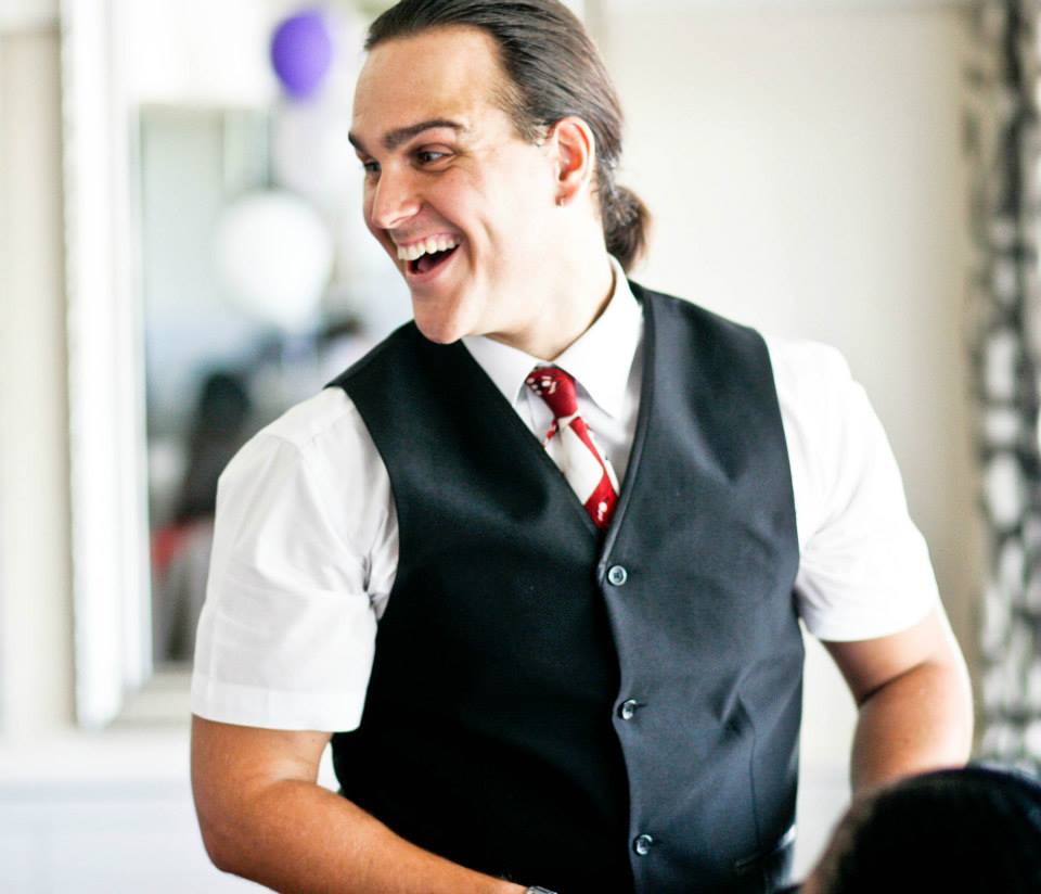 A smiling performer in a vest and tie