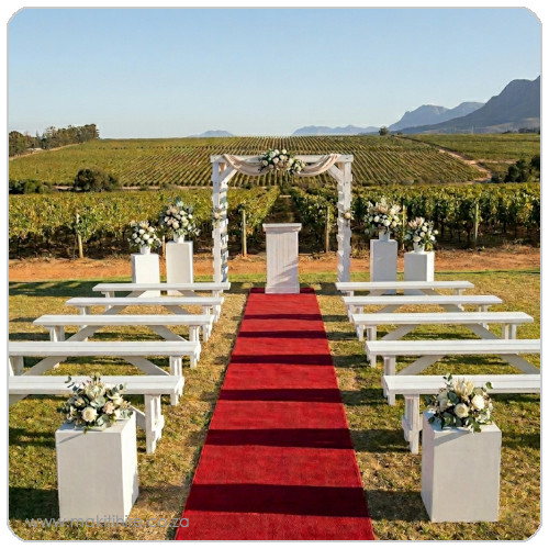 Outdoor wedding ceremony setup with red carpet and floral arrangements
