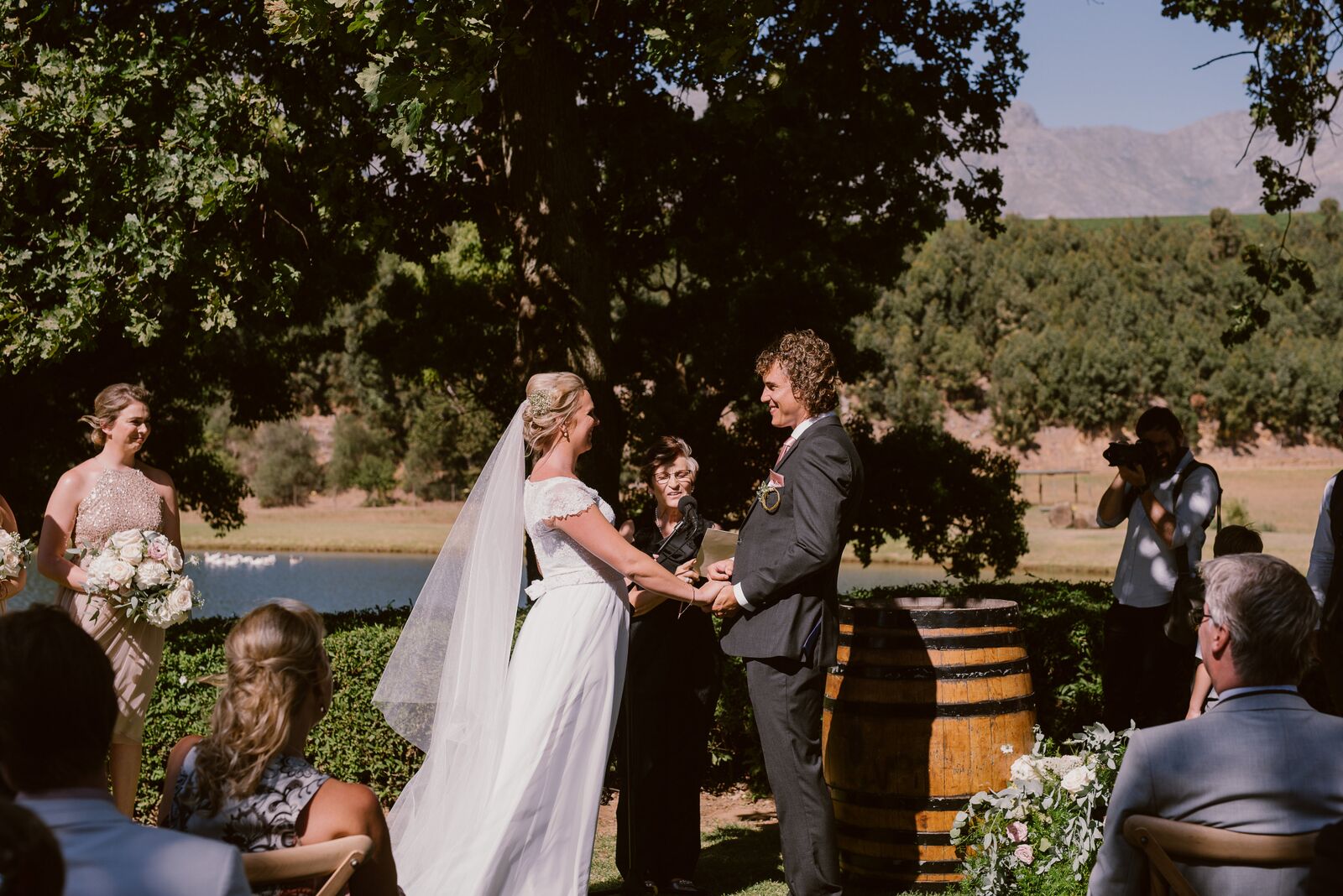 Couple exchanging vows during an outdoor wedding ceremony with guests in attendance.