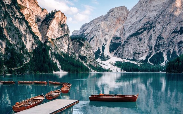 Wooden boats moored by a calm mountain lake.