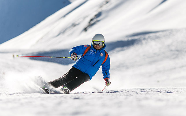 Skier in blue jacket skiing on a snowy mountain