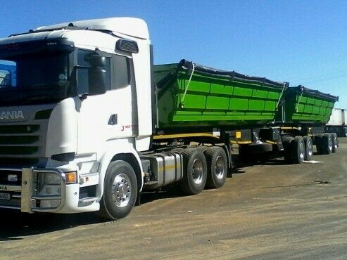 White Scania truck with two green side tipper trailers