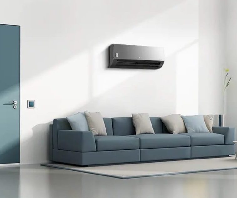 Wall-mounted air conditioner above a blue sofa in a bright room
