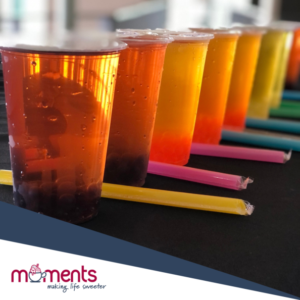 Row of colorful layered drinks in clear cups