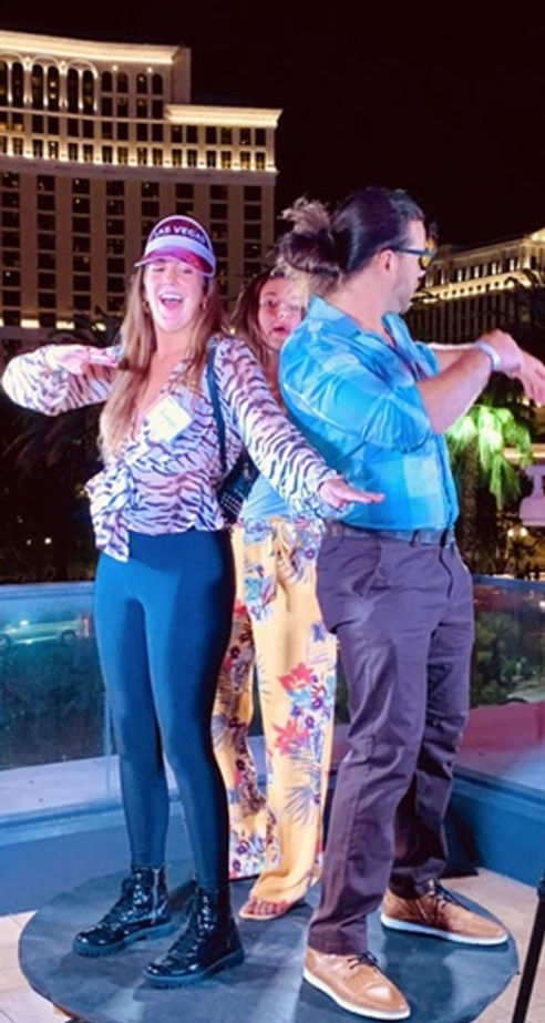Three people using a 360° photo booth setup at night.