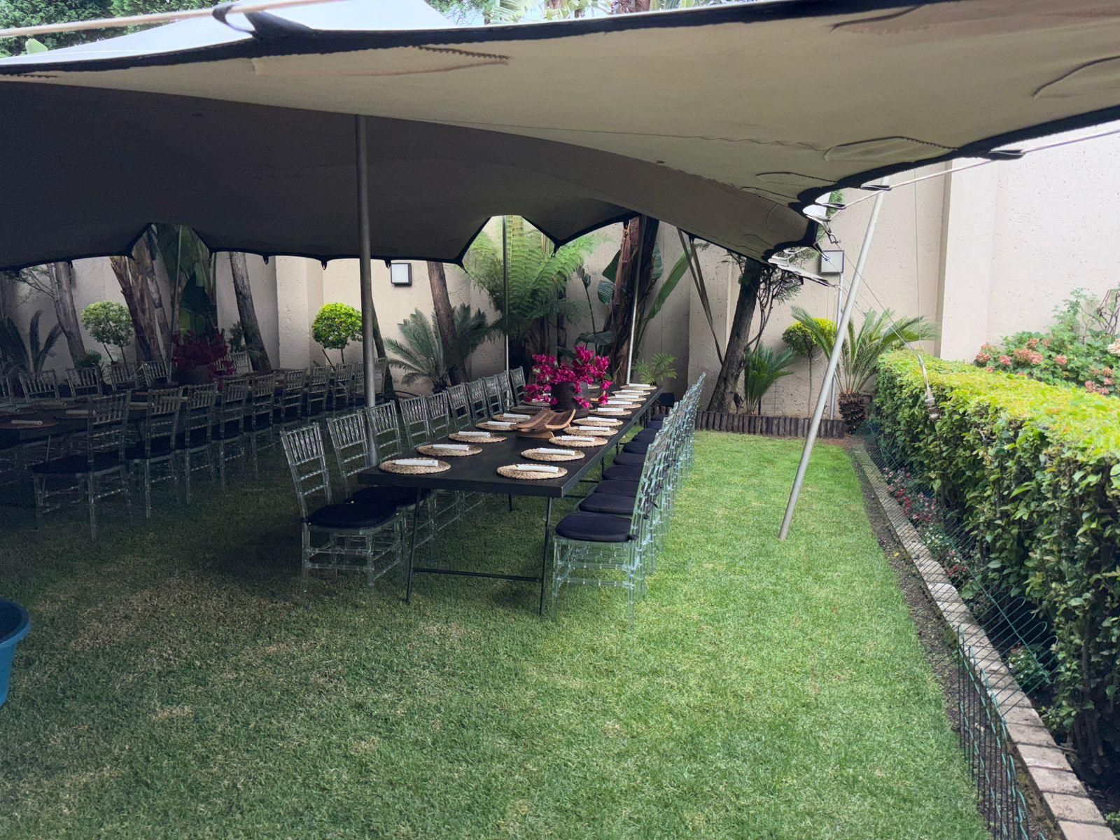 Stretched tent setup with tables and chairs in a garden
