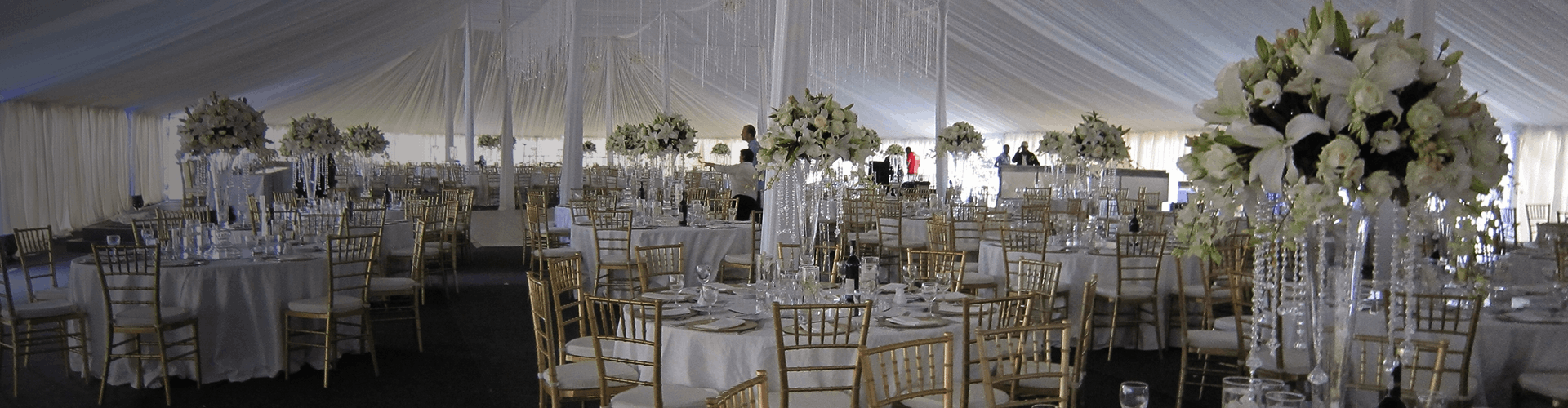 Interior of a marquee with gold chairs and elegantly set tables