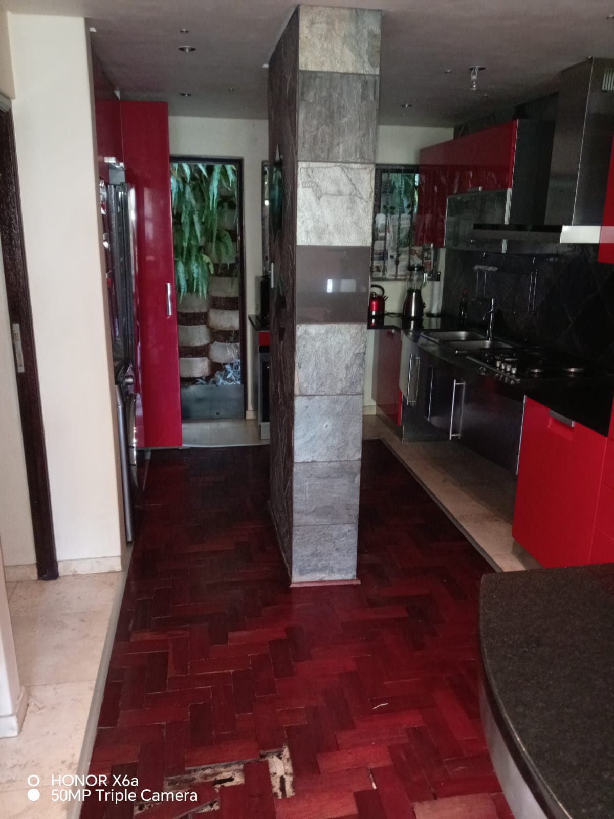 Interior view of a modern kitchen with red cabinets and stone features.