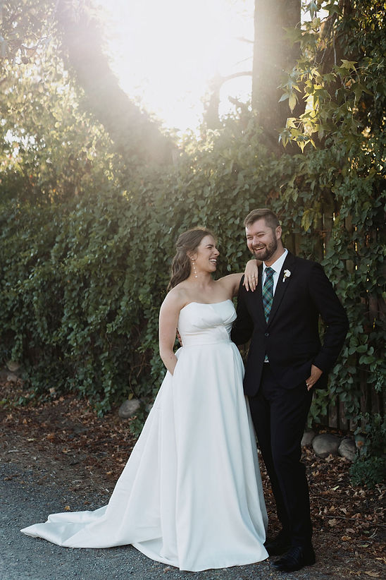Couple in wedding attire smiling outdoors