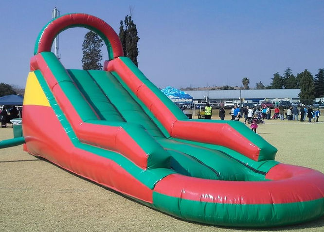 Large red and green inflatable slide set up on grass