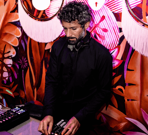 DJ performing at an event with vibrant mural backdrop