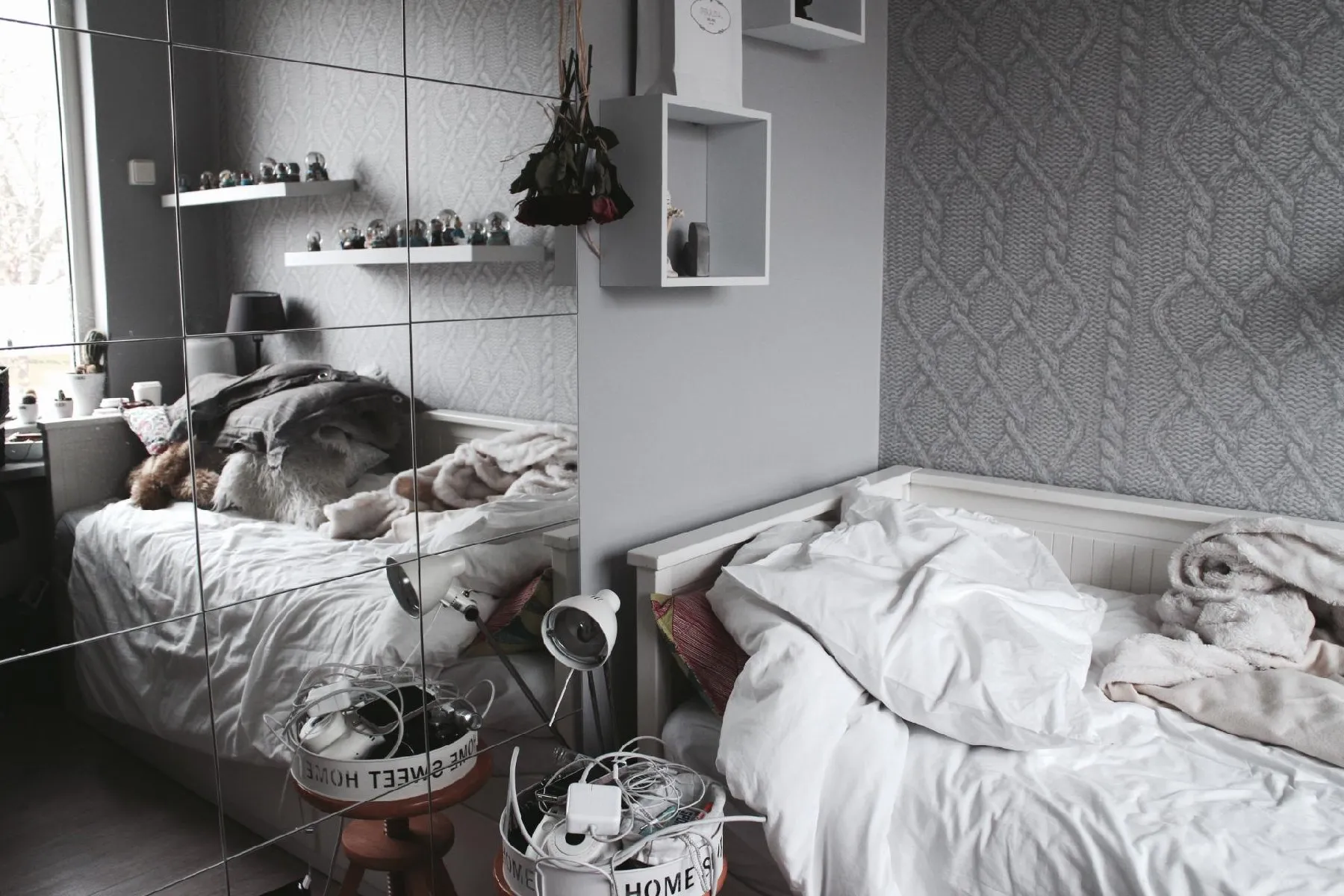Cozy bedroom with mirrored wall and scattered bedding.