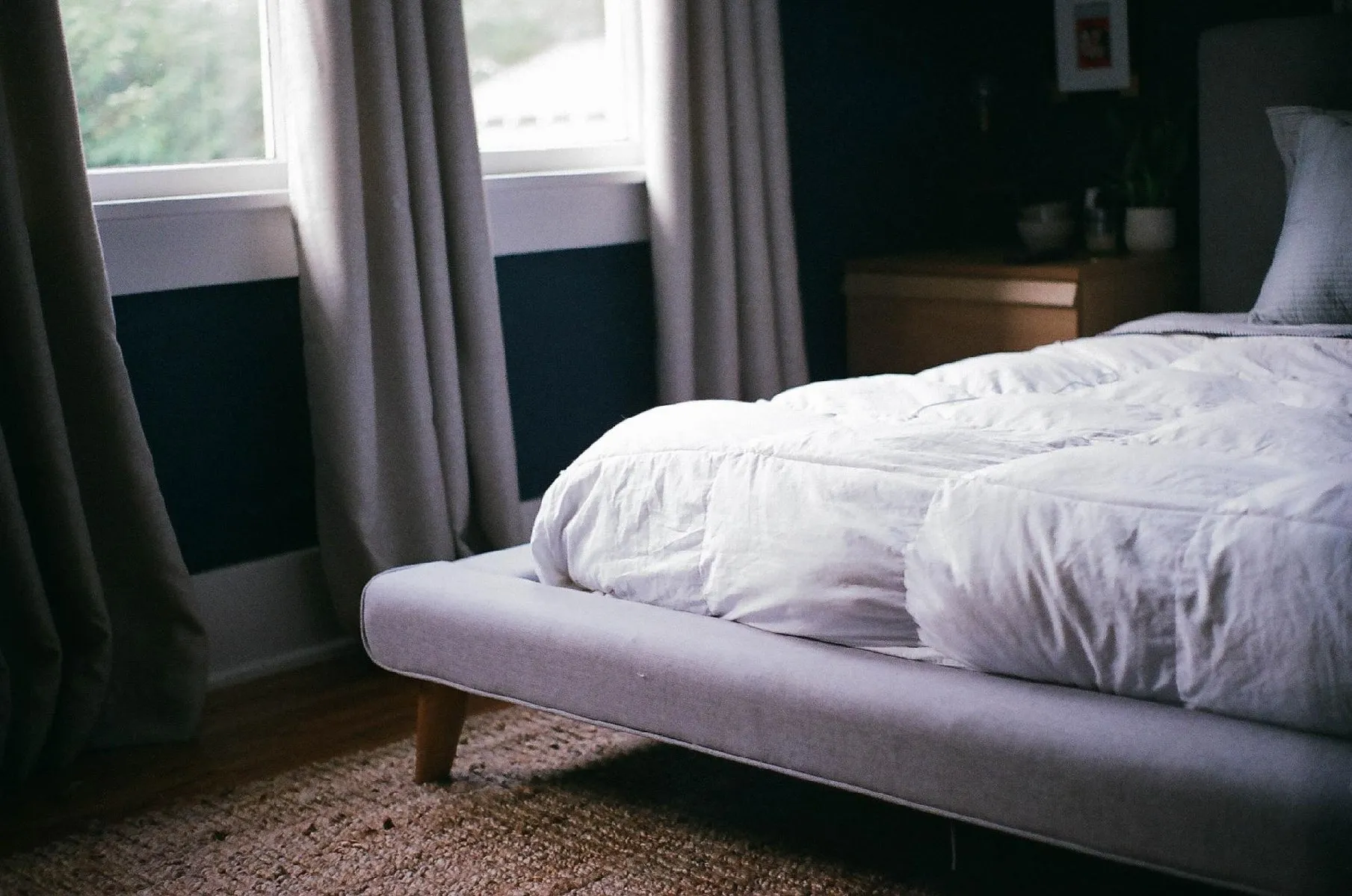 A neatly made bed with white bedding and natural light
