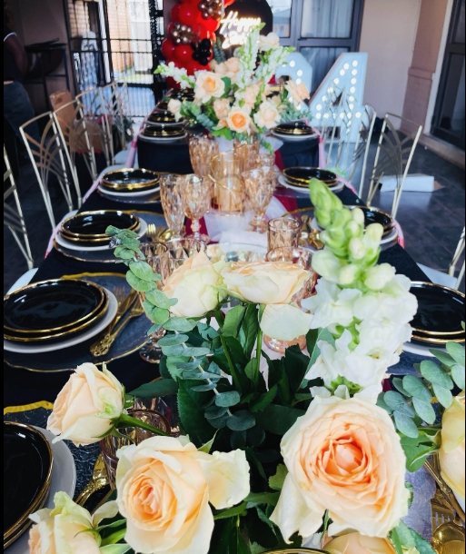 An elegantly set dining table with flowers and black and gold tableware.