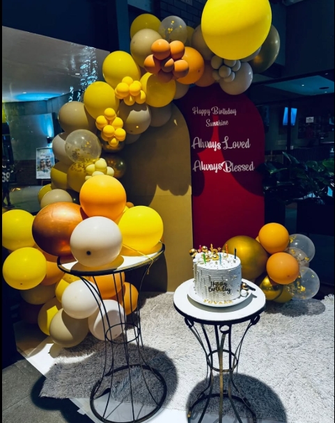 Colorful balloon arch with cake for a birthday celebration.