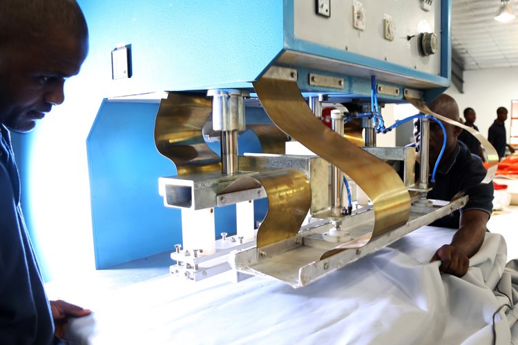 Workers operating a fabric welding machine for stretch tents