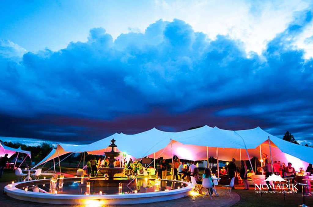 Large stretch tent set up over a fountain at an outdoor event.