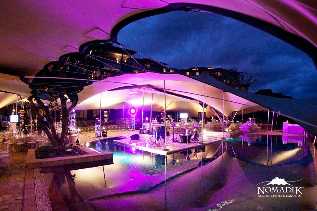 Stretch tent setup by a pool with purple lighting