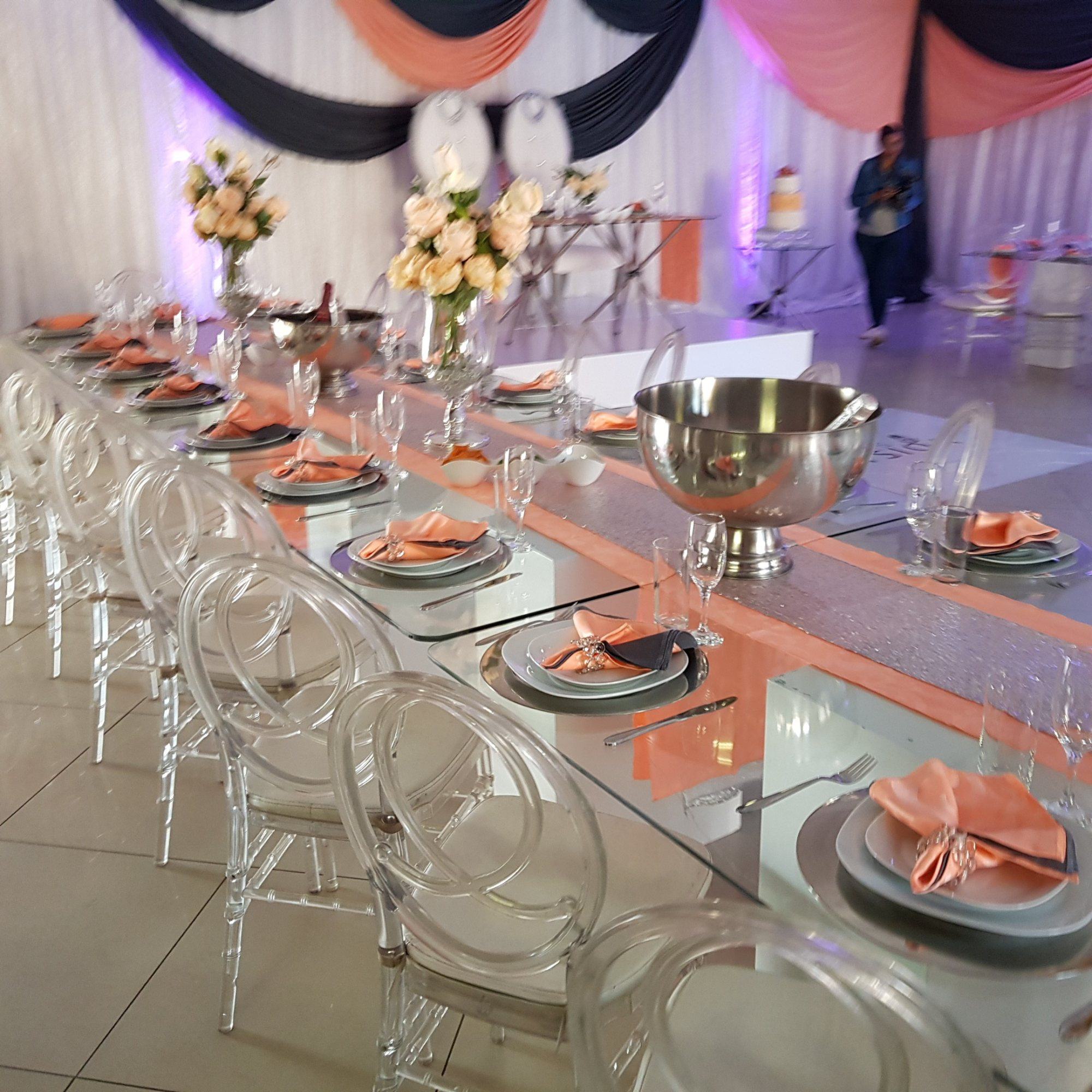 Table set with clear chairs, floral centerpieces, and glassware