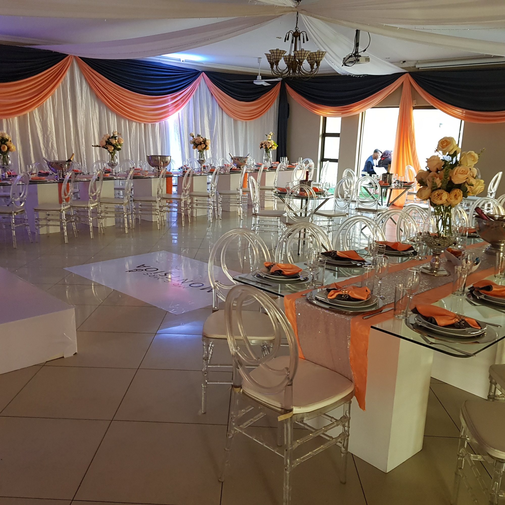 Banquet setup with stylish tables, chairs, and decor in orange and navy.