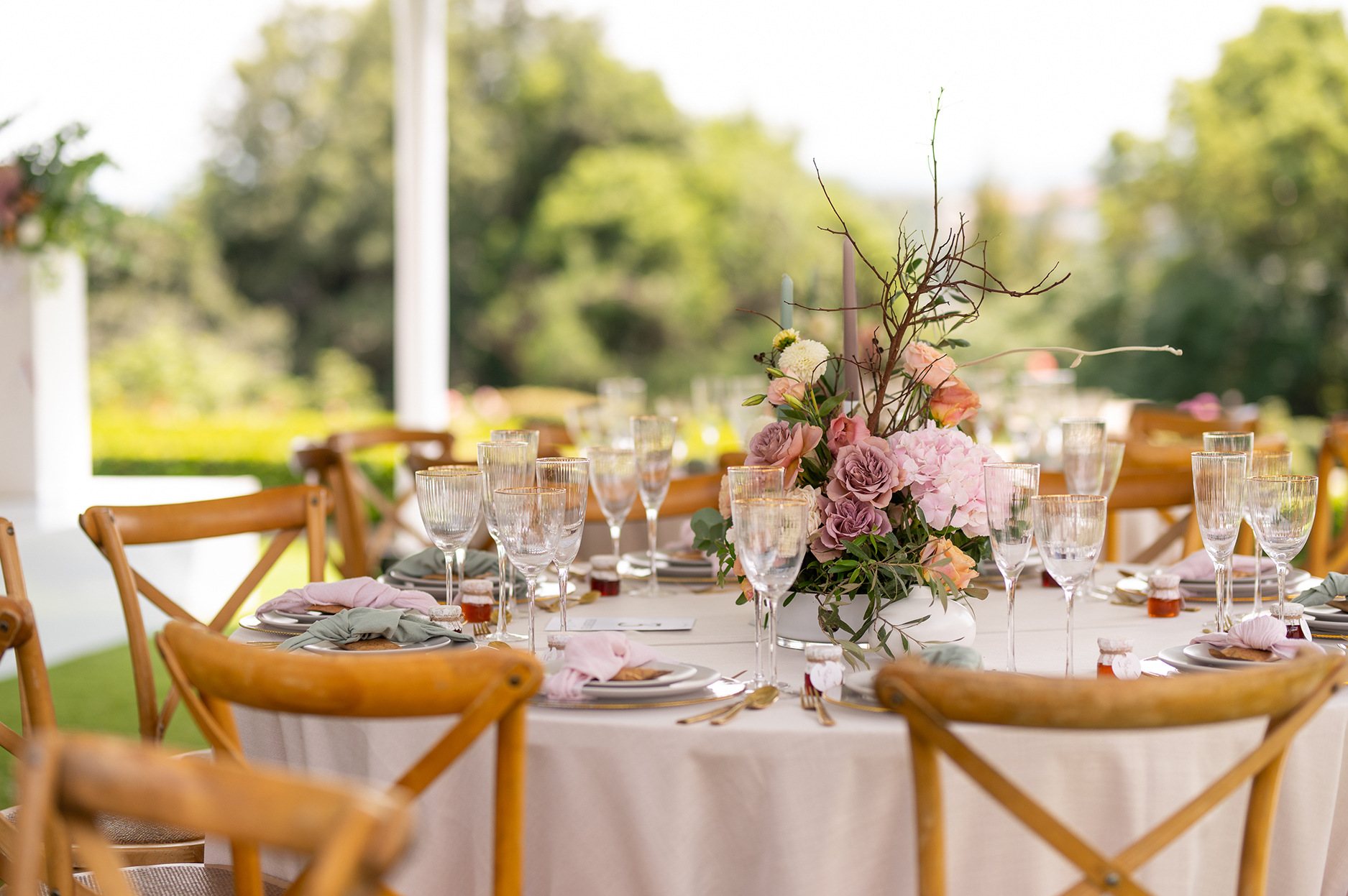 A round table set for dining outdoors with floral centerpiece.