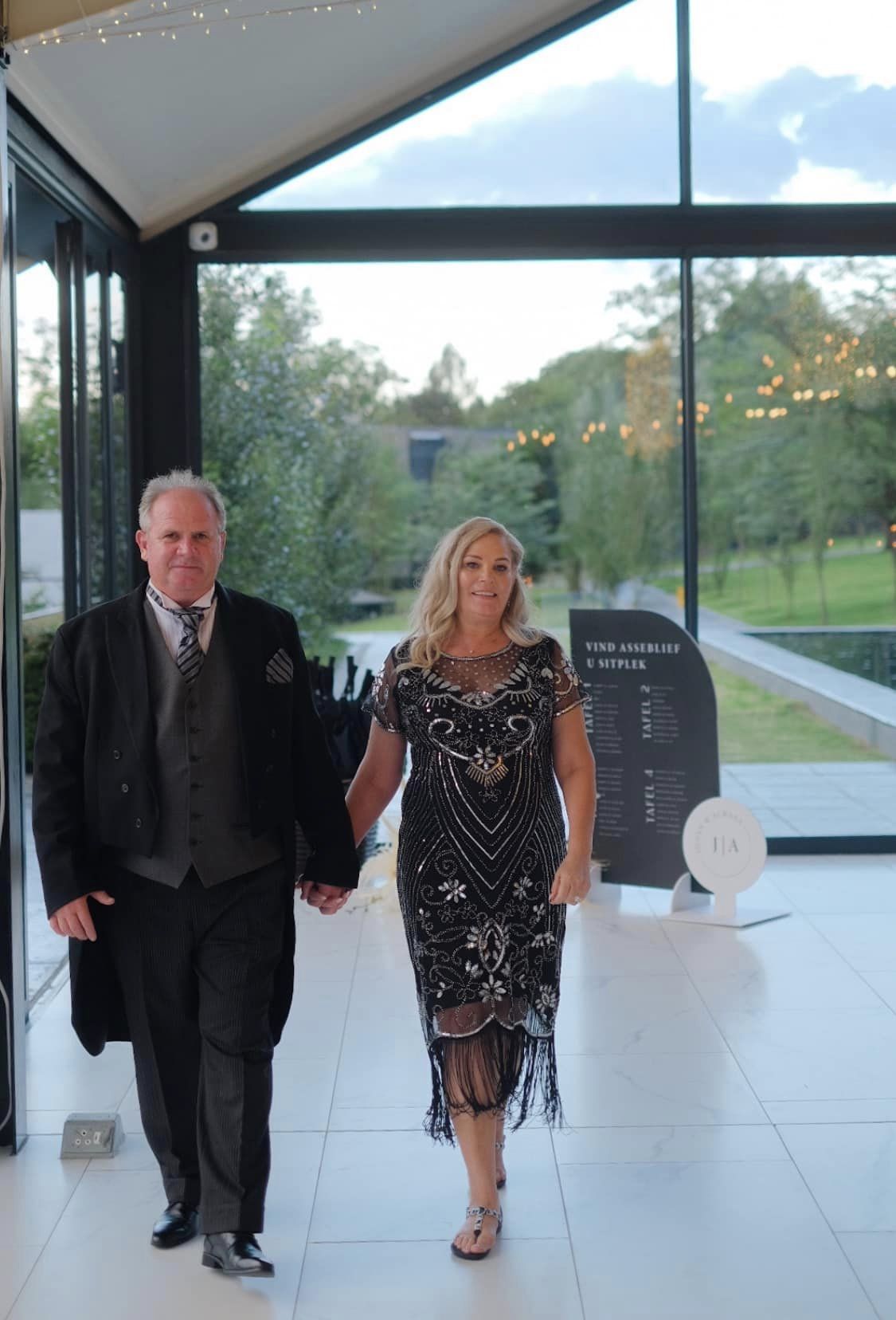Couple entering an event venue with elegant signage in the background.