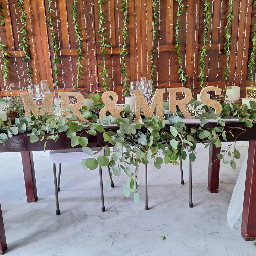 Decorated wedding table with 'Mr & Mrs' sign and greenery.