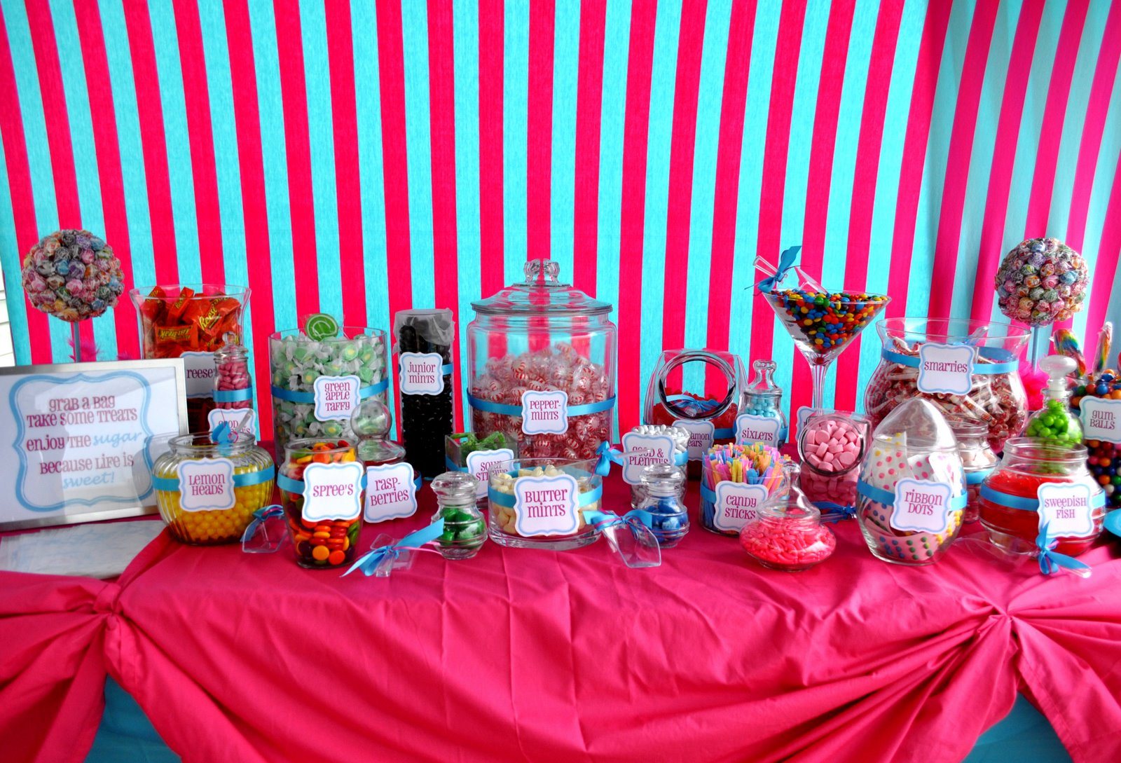 Candy table with jars of colorful sweets and pink fabric