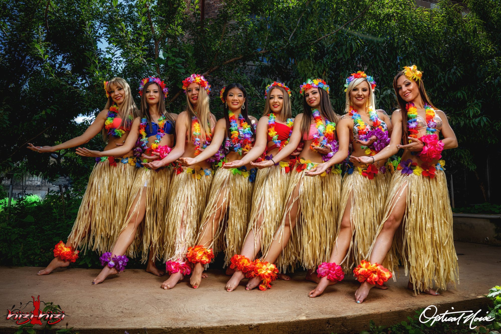Eight dancers wearing hula skirts and floral leis