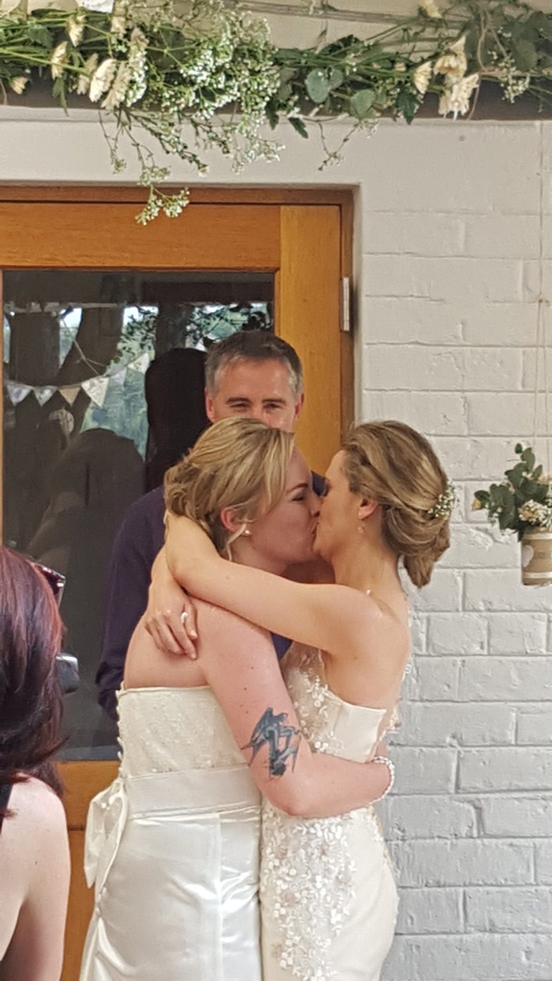 Two brides sharing a kiss in a warm setting