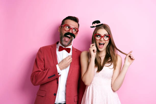 Two people posing with props in a photo booth