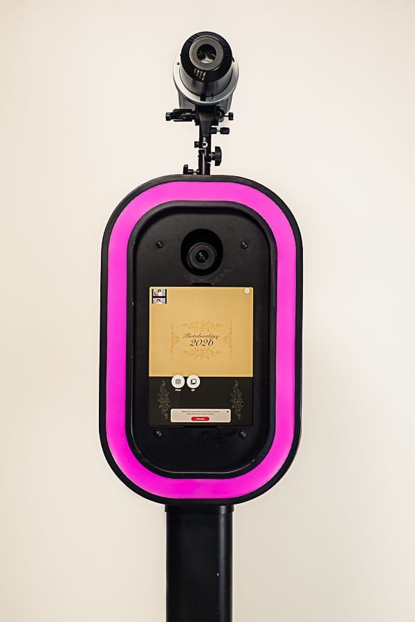 A black 360 video booth with pink accents and a camera.
