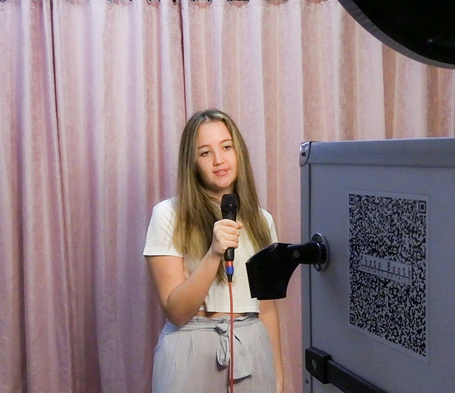 Young woman using a microphone at a mirror photo booth