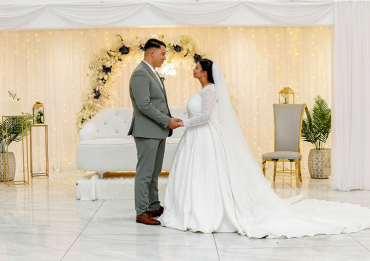 Bride and groom holding hands in a decorated wedding venue.