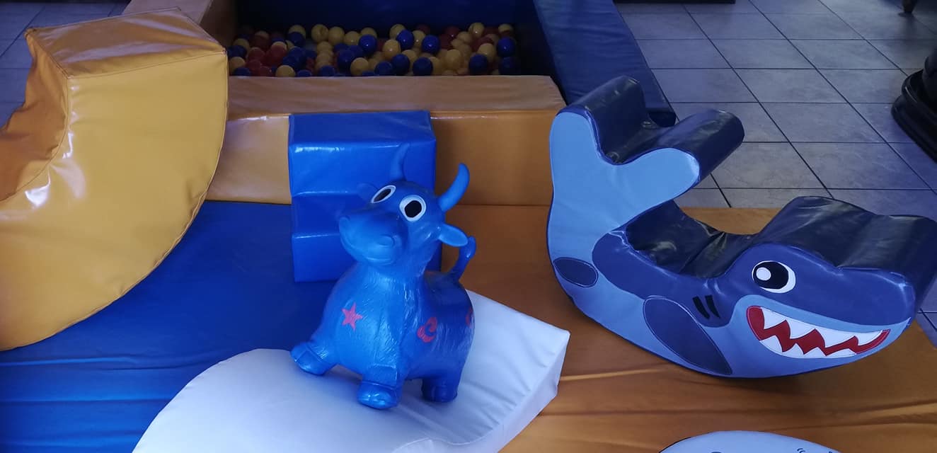 Bright blue shark rocker and cow toy on soft play equipment.