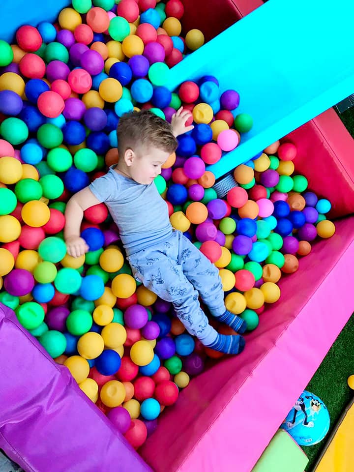 A boy playing in a colorful ball pit.