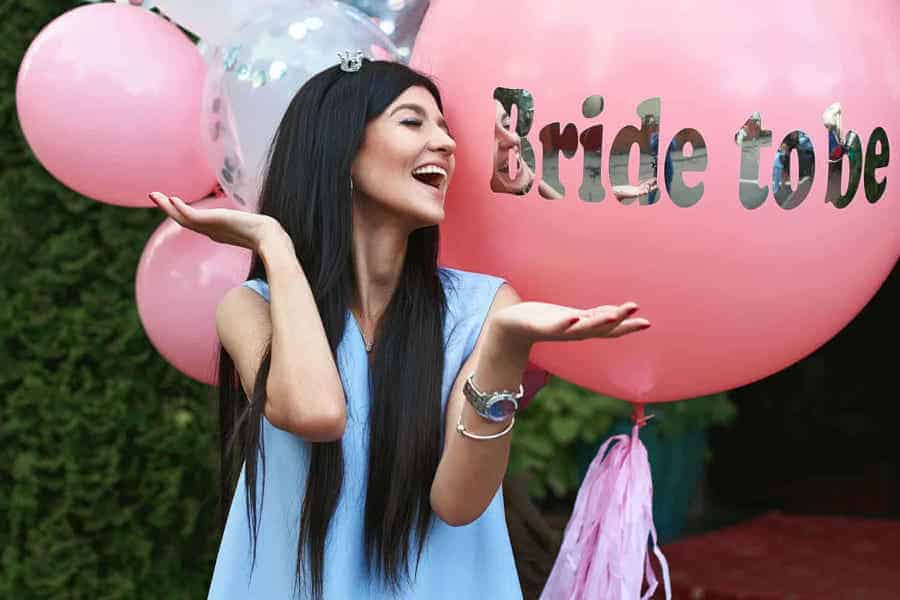 A woman enjoying a party with 'Bride to be' balloons.