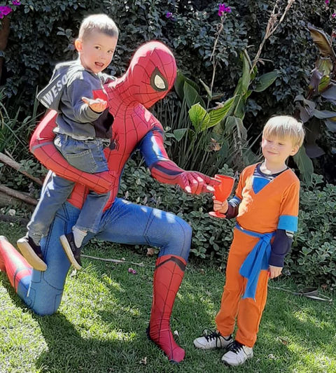 Children with Spider-Man at a kids' party in a garden.