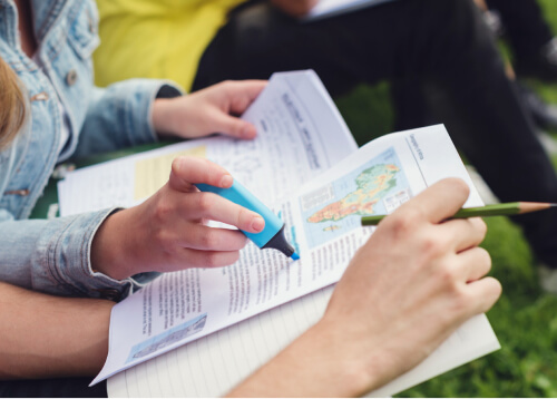 Hands holding printed invitation cards and a pencil.