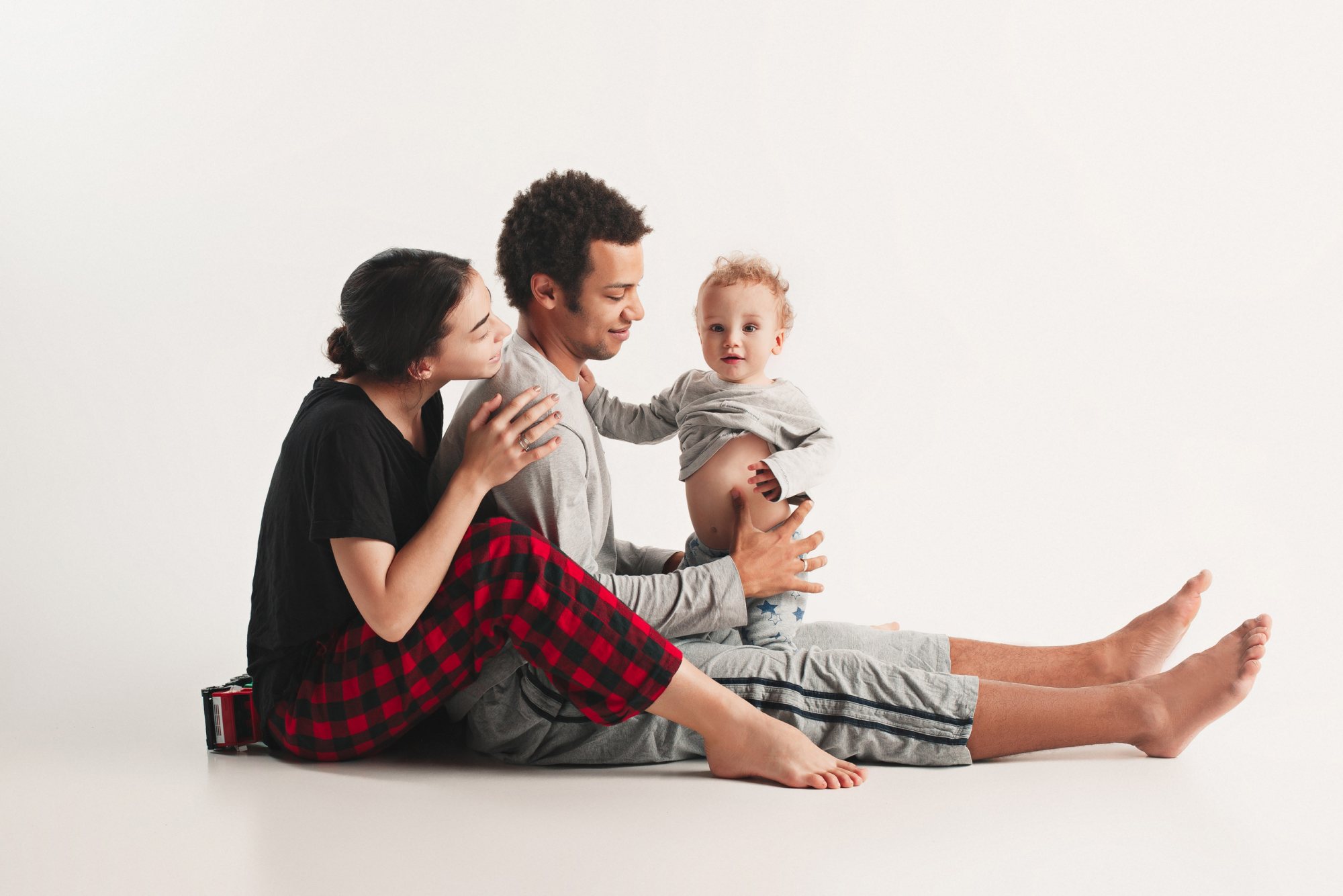 A family sitting together, smiling and interacting in a studio.