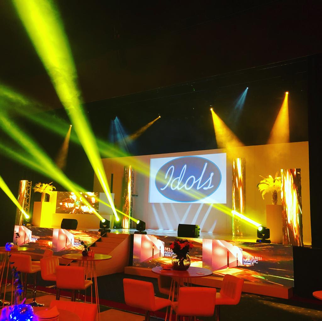 Dynamic stage lighting setup with colorful beams and Idols logo