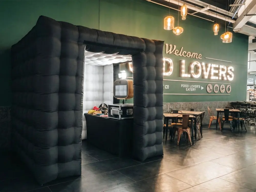 Inflatable black photo booth in a venue with green wall